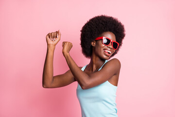 Portrait of optimistic brunette curly lady dance look empty space wear spectacles blue top isolated on pastel pink color background