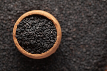Macro Close-Up of Organic Black Sesame seeds (Sesamum indicum) or Black Til with shell in an earthen clay pot (kulhar) on the self background. Top view