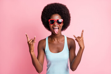 Photo of crazy cool dark skin woman make horned signs music lover summer isolated on pink color...