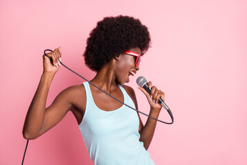 Photo of pretty brunette volume hair dark skin woman sing loud mic isolated on pastel pink color...