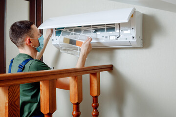 Male technician cleaning air conditioner indoors