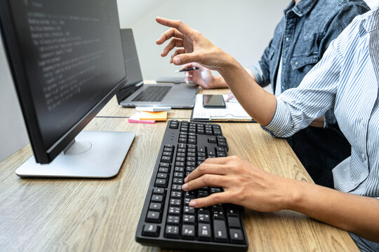 Two professional programmer cooperating and working on web site project in a software developing on desktop computer at company, codes and typing data code, Programming with HTML, PHP and javascript