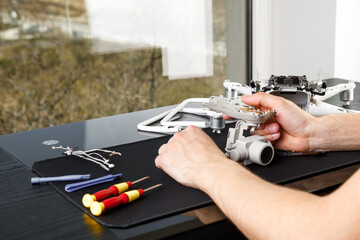 Close-up Of Person's Hand Repairing Drone Using Screwdriver. a man working in a repair shop