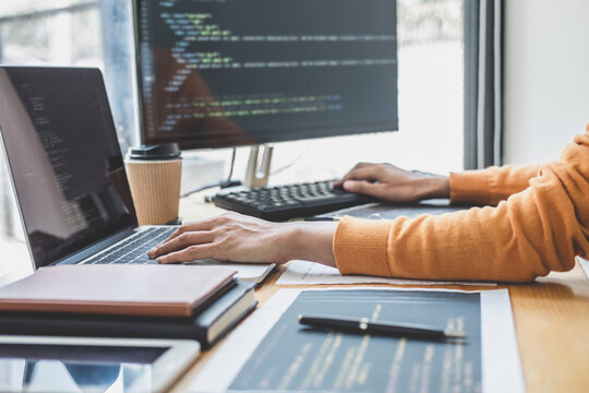 Young Professional programmer working at developing programming and website working in a software develop company office, writing codes and typing data code, Programming with HTML, PHP and javascript