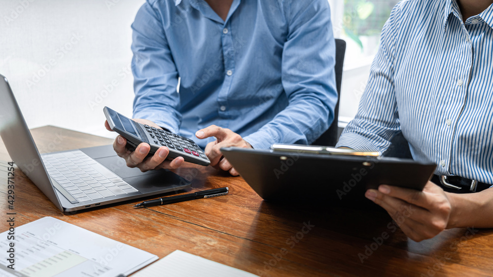 Aufkleber Close up of two business colleagues looking data on clipboard and using calculator to calculate finance