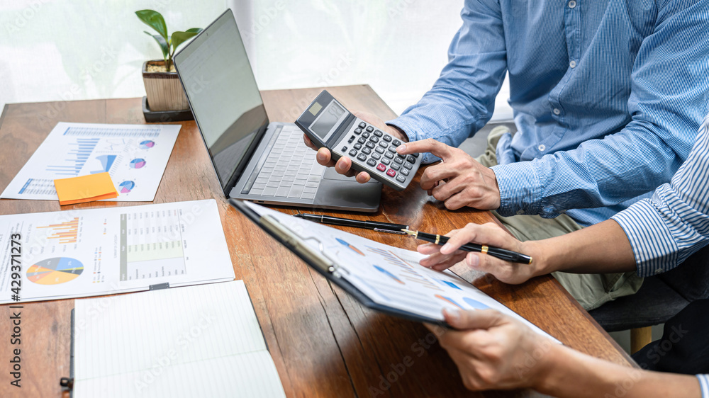 Aufkleber Close up of two business colleagues looking data on clipboard and using calculator to calculate finance