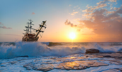 Old Sailing-ship in storm sea, dramatic sunset in the background