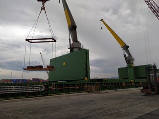 a cargo ship and cranes and machinery in the port of Bilbao, Spain, one morning at dawn