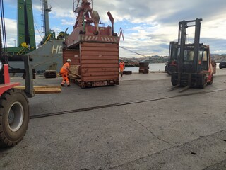 a cargo ship and cranes and machinery in the port of Bilbao, Spain, one morning at dawn