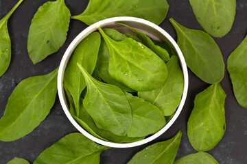 Spinach leafs in bowl on wooden background
