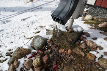 Water dripping from downspout after the snow melts in spring