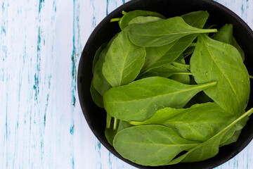 Spinach leafs in bowl on wooden background