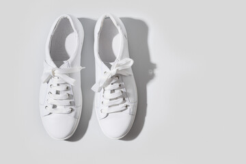 White gumshoes on grey background with copy space. Washing and cleaning concept. Regular care about shoes. Top view.