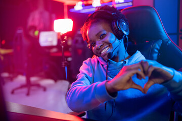 Streamer African American beautiful girl shows heart sign with hands professional gamer playing...