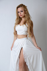 Polish model posing with white top, long white dress with cut, showing her legs.