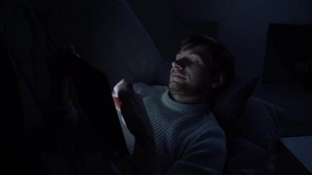 A man lying in bed uses a smartphone