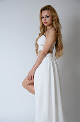 Fototapeta na wymiar Polish model posing with white top, long white dress with cut, showing her legs.