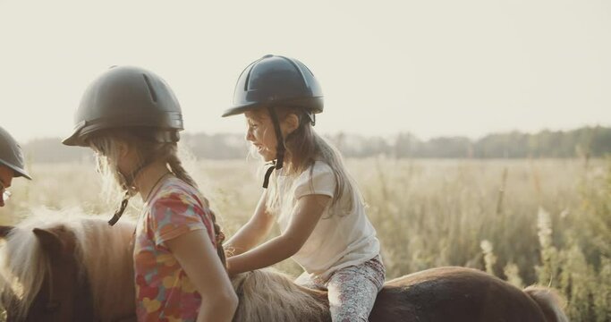 Happy kids at the summer field, horseback riding far away from the city. Beautiful movie about horse riding camp, playful girls learn how to care about horses and how to prepare for riding.