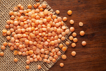 Macro Close-up of Organic Masoor dal (Lens culinaris) or Whole Pink Dal on Jute mat and wooden top.