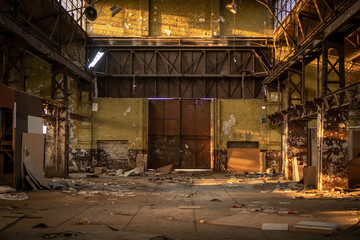 Old abandoned brick and concrete warehouse with a lot of rubbish around during the late afternoon spring sunset.