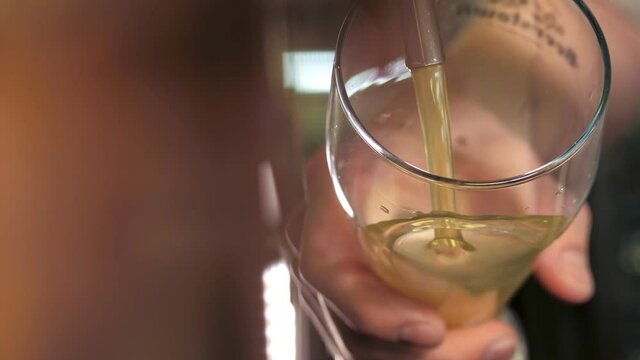 The bartender pours a light beer into a foaming glass. A row of beer steel taps in a dark pub or bar. Taps for draught beer in a modern bar. The bartender pours craft beer at the bar. Close-up