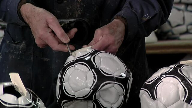 Worker Hands Inserting a Bladder into an Inflatable Soccer Ball at a Soccer Ball Factory. Close Up.