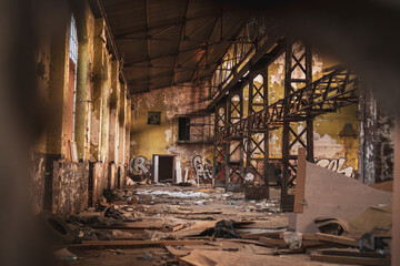 Old abandoned brick and concrete warehouse with a lot of rubbish around during the late afternoon spring sunset.