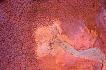 Aerial drone view of industrial chemicals dump site from ironlworks, dry red soil with animal paw prints, unique texture.