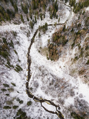 Obraz premium Aerial view of winding river, bridge, island and forest in Riezupe river nature park in winter day, Latvia. 