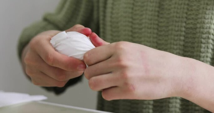 girl wraps an egg in a white napkin before painting, preparing for the holiday