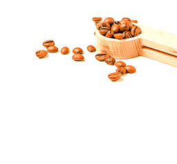 Coffee beans in a wooden spoon isolated on a white background. The coffee beans are scattered. Copy space for text. Selective focus.