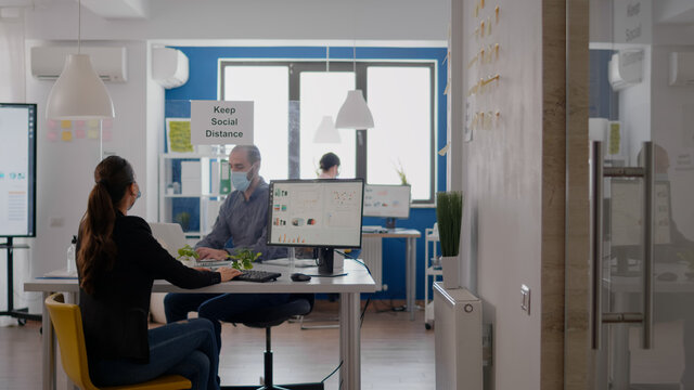Businessman with face mask touching elbow with his collegue to avoid infection with coronavirus. Coworkers mantain social distancing while working on communication company project