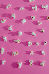 Popcorn scattered on a pink background. 