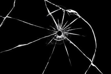 The effect of cracks on broken glass from a shot of a weapon. A hole in the glass of the bullet. © malshak_off