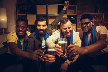 Group of friends watching TV, sport match together. Emotional fans cheering for favourite team, watching on exciting game.