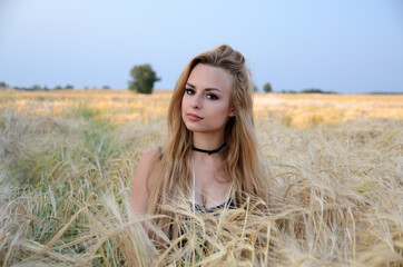 Naklejka na ściany i meble Charming, young woman posing in field of rye. Woman portrait in open field.