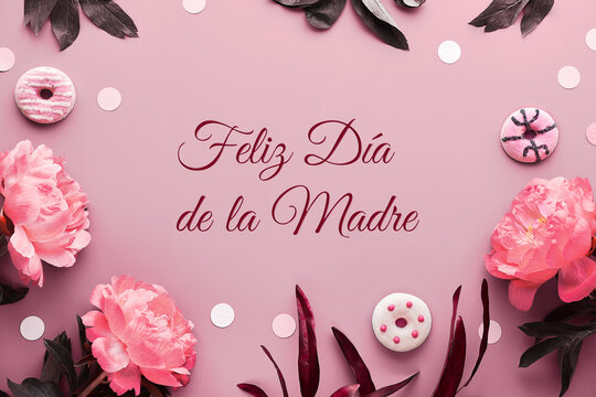 Feliz Dia de la Madre means Happy Mother's Day in Spanish. Pink peony flowers, leaves and sweet doughnuts, donuts. Monochrome pink floral arrangement. Desaturated flat lay, top view on pink paper.