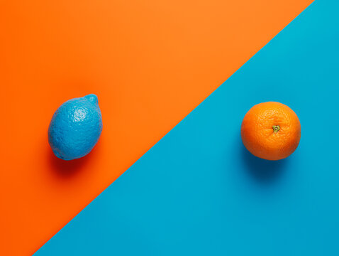 Citrus layout with blue painted lemon and orange on two tone vibrant background. Minimal fruit food concept. Vegetarian healthy vitamin diet banner. Flat lay, top view.