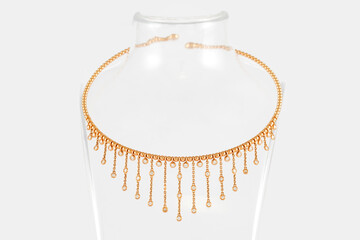 Golden necklace with diamonds on transparent jewelry neck stand in boutique. Yellow gold with diamonds, fashion jewelry.