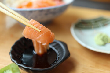 Salmon sashimi in chopsticks dipping with soy sauce