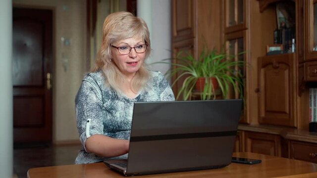 Senior successful businesswoman using laptop at home living room office, professional elderly 55s female employer receiving good news excited achieve cheerful smiling woman with notebook indoors