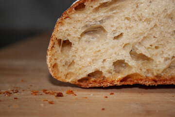 Close up of freshly baked bread  on wooden table. Bread crumbles.