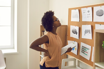 Young african american woman employee brainstorming standing near board with project result looking...