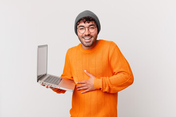 nerd man with computer laughing out loud at some hilarious joke, feeling happy and cheerful, having...