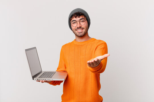 nerd man with computer smiling happily with friendly, confident, positive look, offering and showing an object or concept