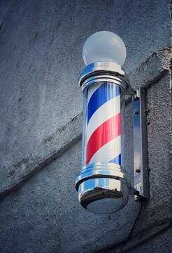 A colourful old fashioned rotating barbers pole outside a hairdresser salon with copy space