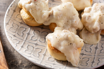 Traditional American biscuits and gravy for breakfast on wooden table. Close up
