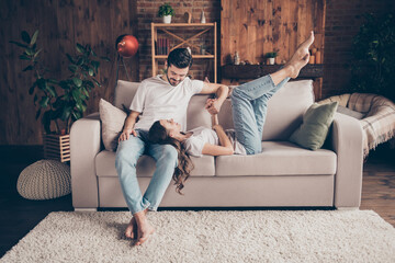 Portrait of two attractive cheerful people lying on divan having fun talking free time weekend at...