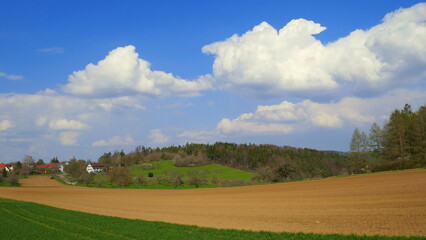 idyllisches Dorf Mindersbach am Rand von  Feld und Wiesen unter schönem Wolkenhimmel im Frühling	