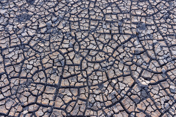 Pattern of cracked ground at the seashore. Brown, beige, light tan and grey blue colored background.